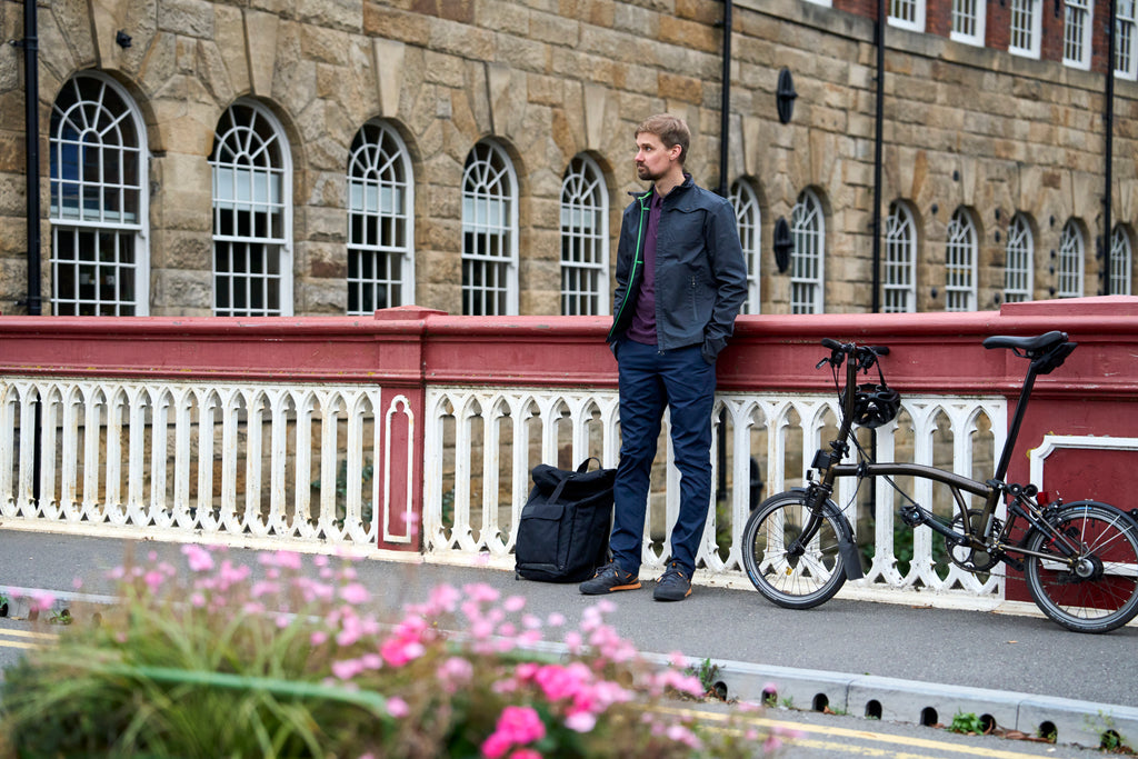 Man standing beside a bike wearing a Harrington jacket